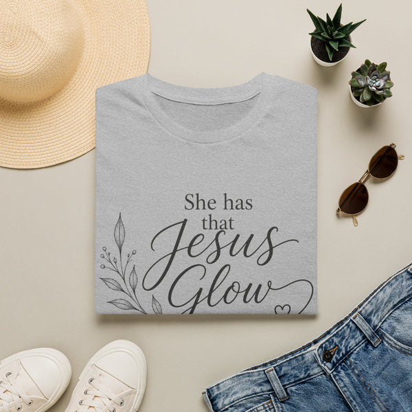 Gray t-shirt with 'She has that Jesus Glow' text, surrounded by casual items on a light surface | Faithful Finds