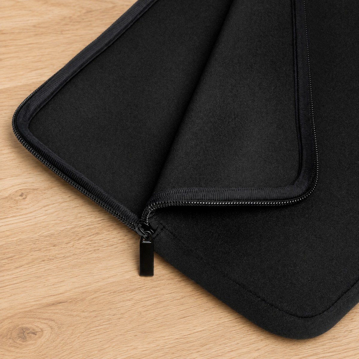 A close-up of a black zippered sleeve or pouch laid on a light wood surface, showing the fabric texture and zipper detail | Faithful Finds