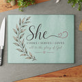 Tempered glass cutting board with 'She Cooks Serves Loves — All to the Glory of God' script on a mint background.