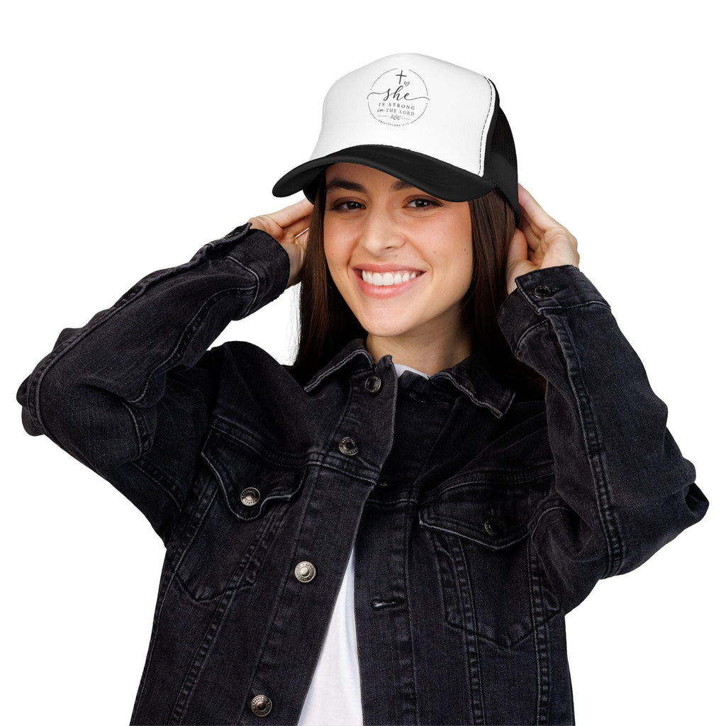 Structured foam trucker hat with 'She Is Strong In The Lord' faith text on the front panel, breathable mesh back.