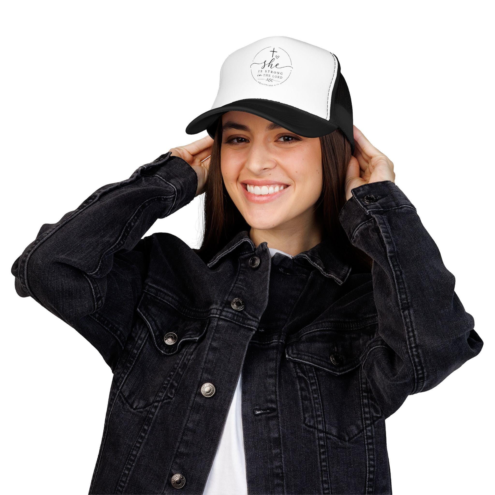 Structured foam trucker hat with 'She Is Strong In The Lord' faith text on the front panel, breathable mesh back.