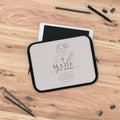 A tablet sleeve with a black border and a light gray printed design reading 'MADE for more' with a rose and cross illustration, placed on top of a tablet on a wooden desk with pencils and binder clips around it | FaithfulFindsNZ
